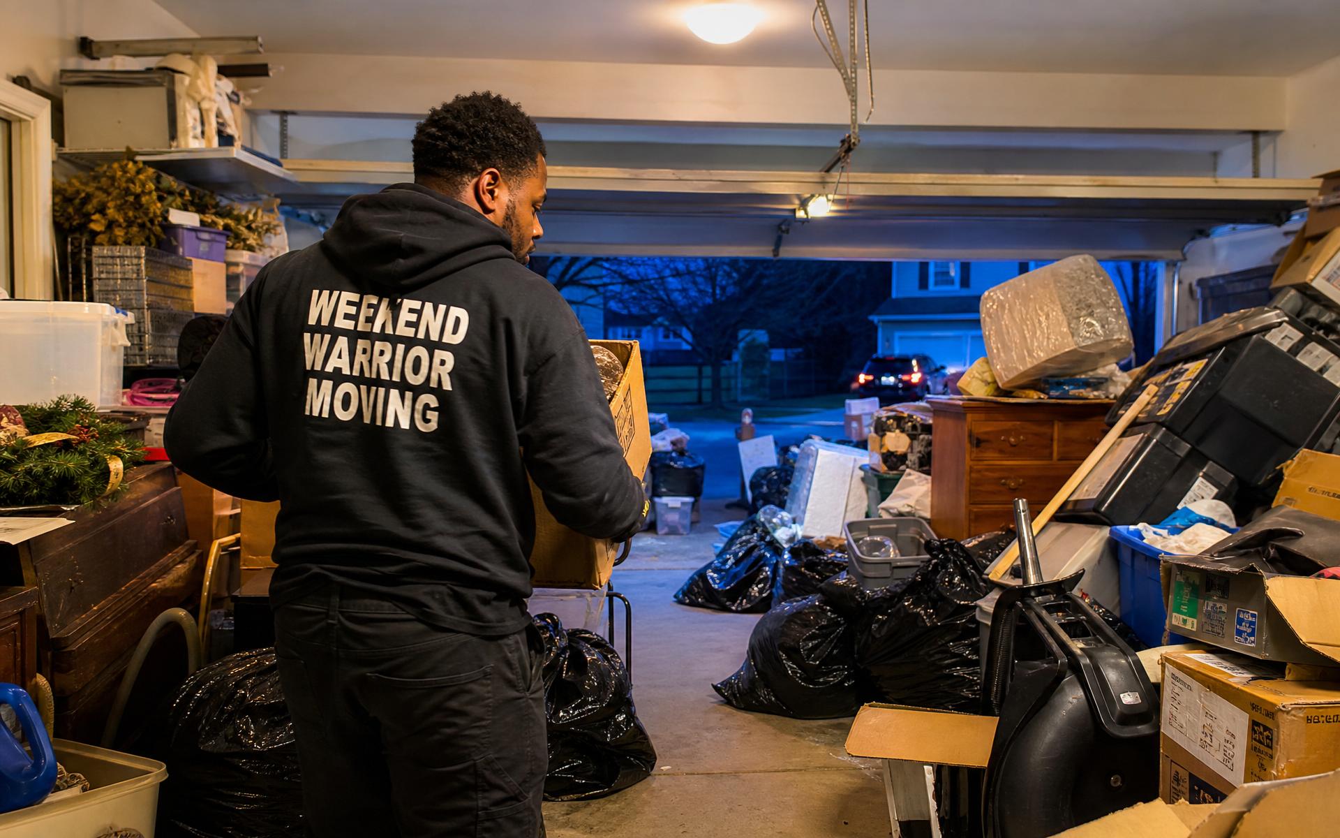 Weekend Warrior Moving crew hauling items out of a Kansas City garage at dusk